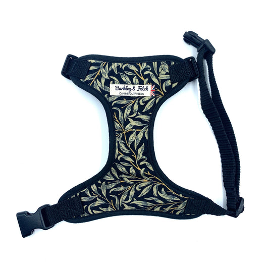 A black fabric dog harness with a floral pattern in a William Morris design, featuring adjustable straps and a metal D-ring.
