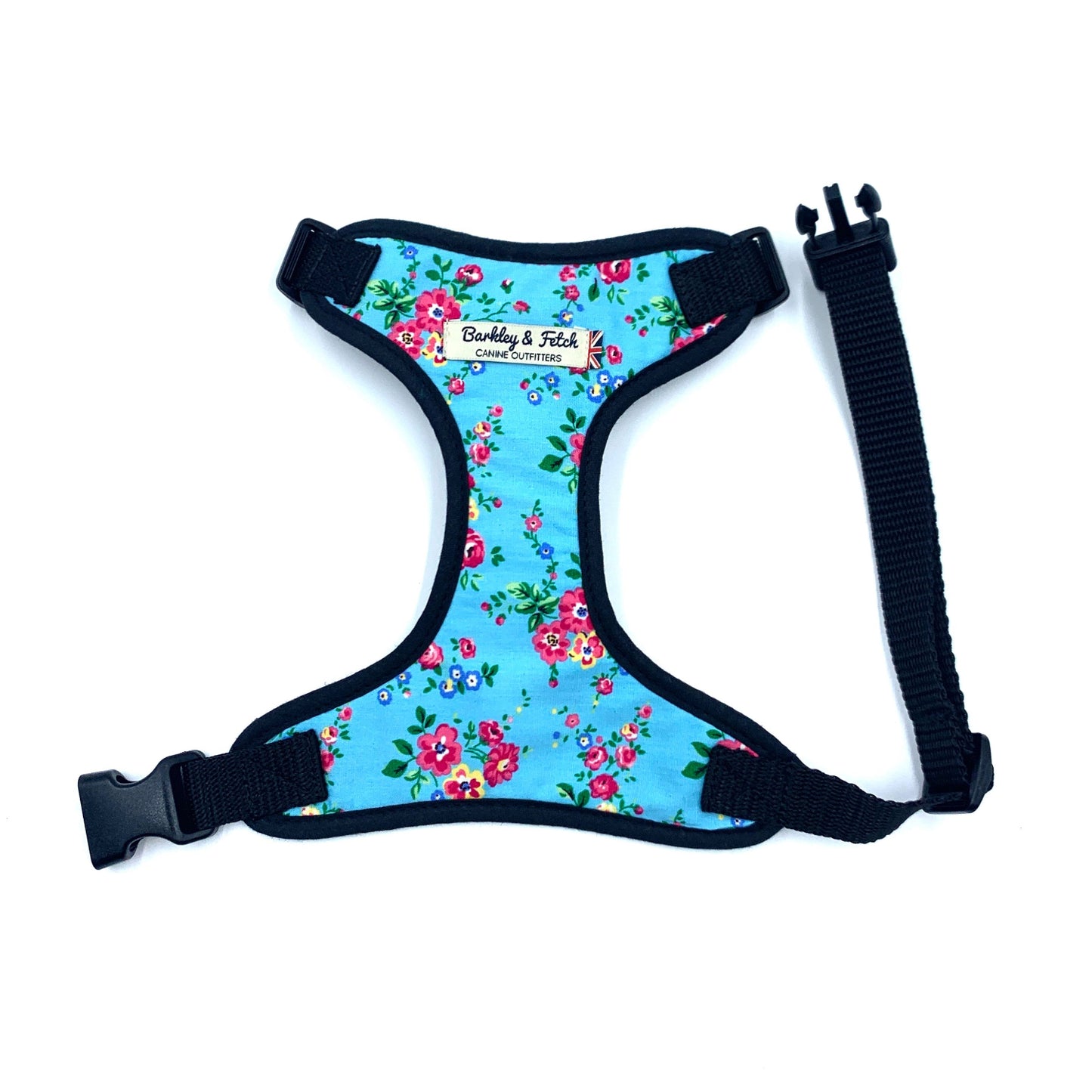 A blue floral fabric dog harness with black trim, side release buckle, and D-ring.