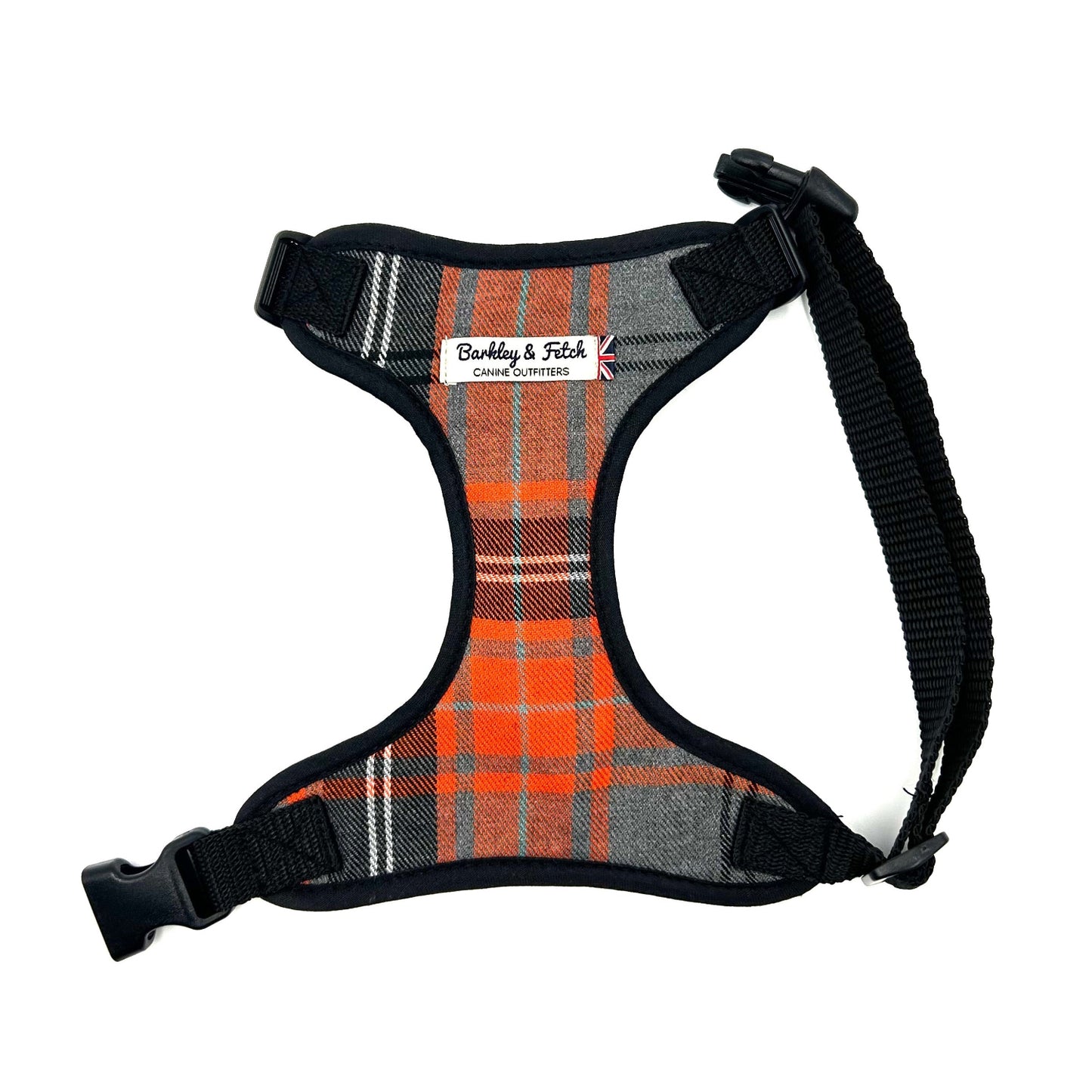An orange and grey tartan soft dog harness with a label showing the brand name and website.