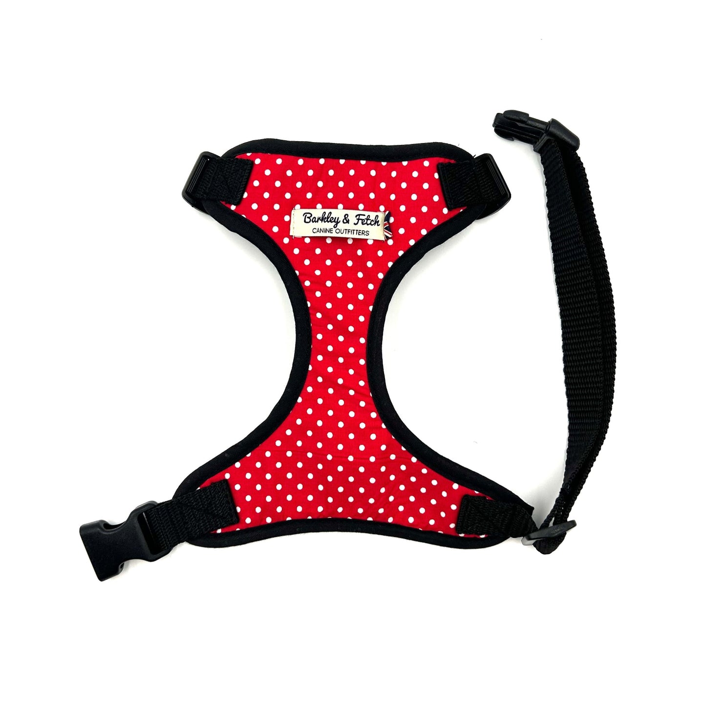 A red and white polka dot dog harness with black straps and a welded heavy duty d-ring, adjustable at neck and girth with side release buckle.