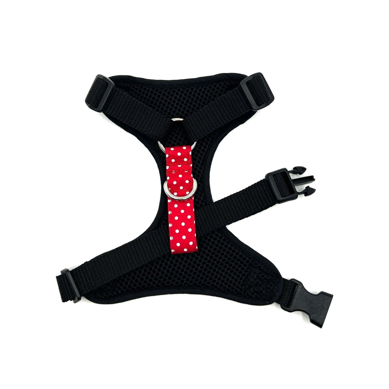 Black dog harness with a red and white polka dot buckle on a white background