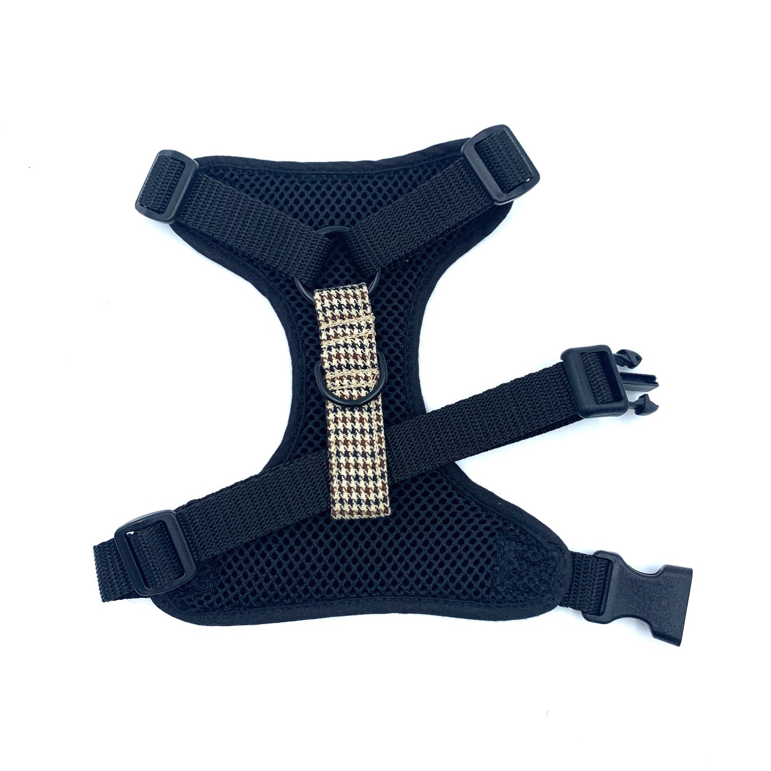 Black dog harness with a gold buckle on a white background