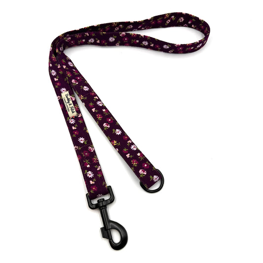 Floral patterned dog leash with a black clip on a white background