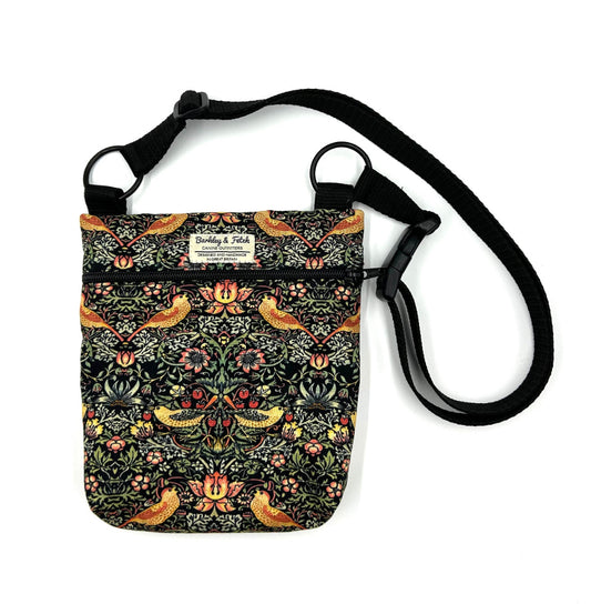 A black shoulder bag with a William Morros floral and bird pattern, made of canvas, with an adjustable strap and a brand label that reads 'Barkley and Fetch'.