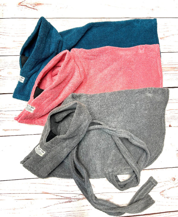 Three folded dog towels in blue, pink, and gray on a wooden surface. Handmade by Barkley and Fetch on our UK workshop