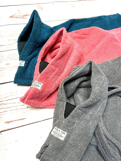 Three bathrobes in blue, pink, and gray on a wooden surface. Handmade by Barkley and Fetch on our UK workshop