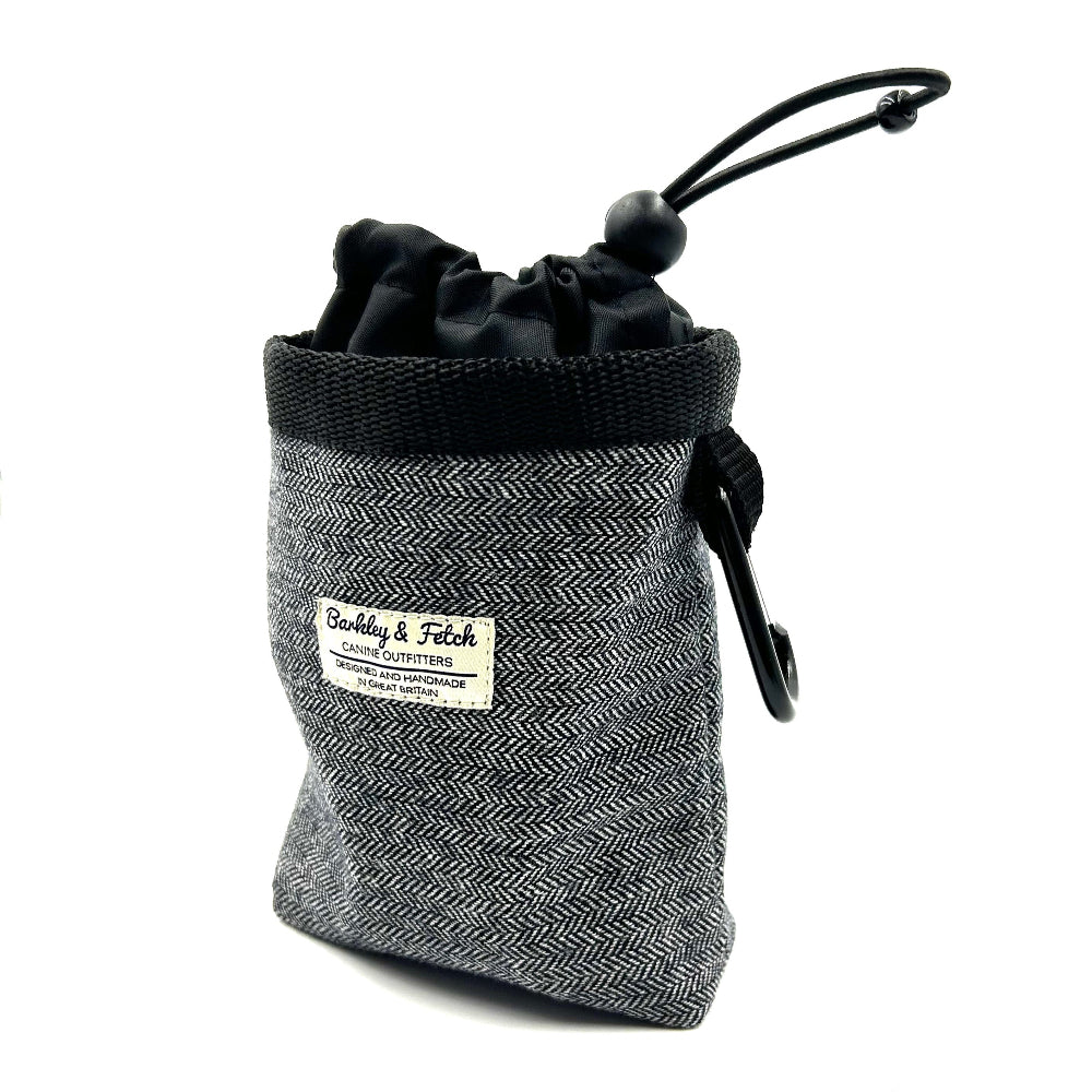 A grey herringbone patterned dog treat bag with a black elasticated drawcord closure and a label that reads 'Barkley & Fetch'.