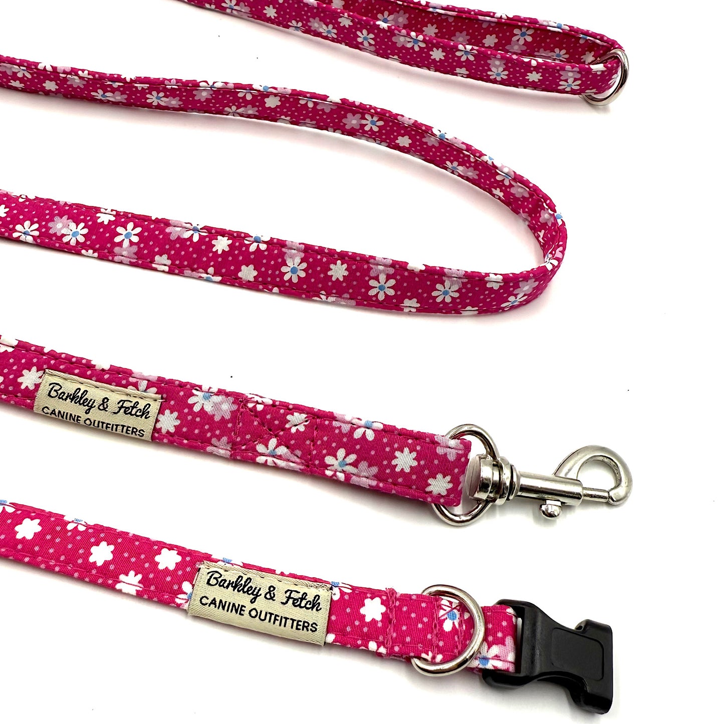 Pink floral patterned dog leash with metal clip and branded tag on a white background
