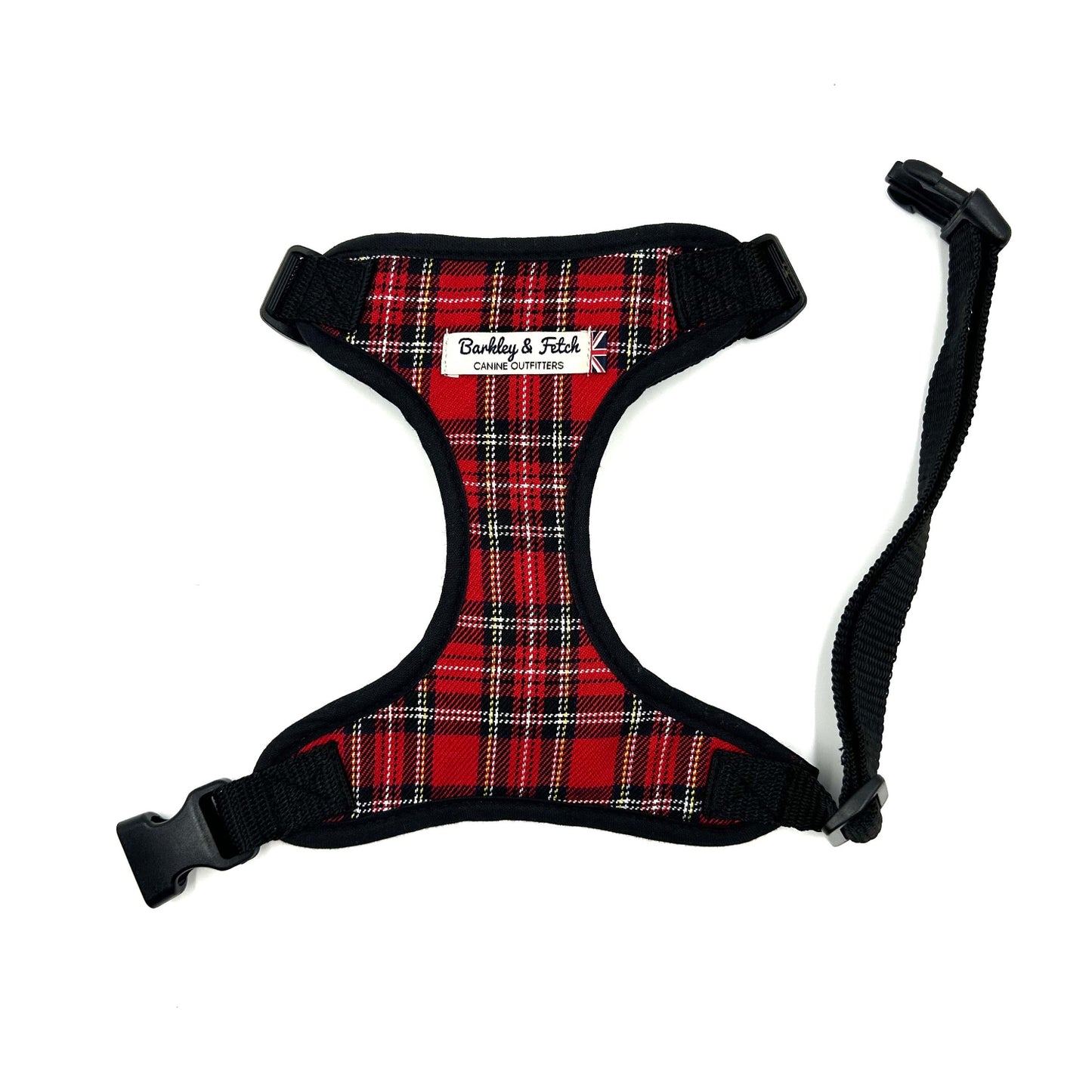 A red and black tartan fabric dog harness with adjustable straps and a metal D-ring, displayed on a white background.