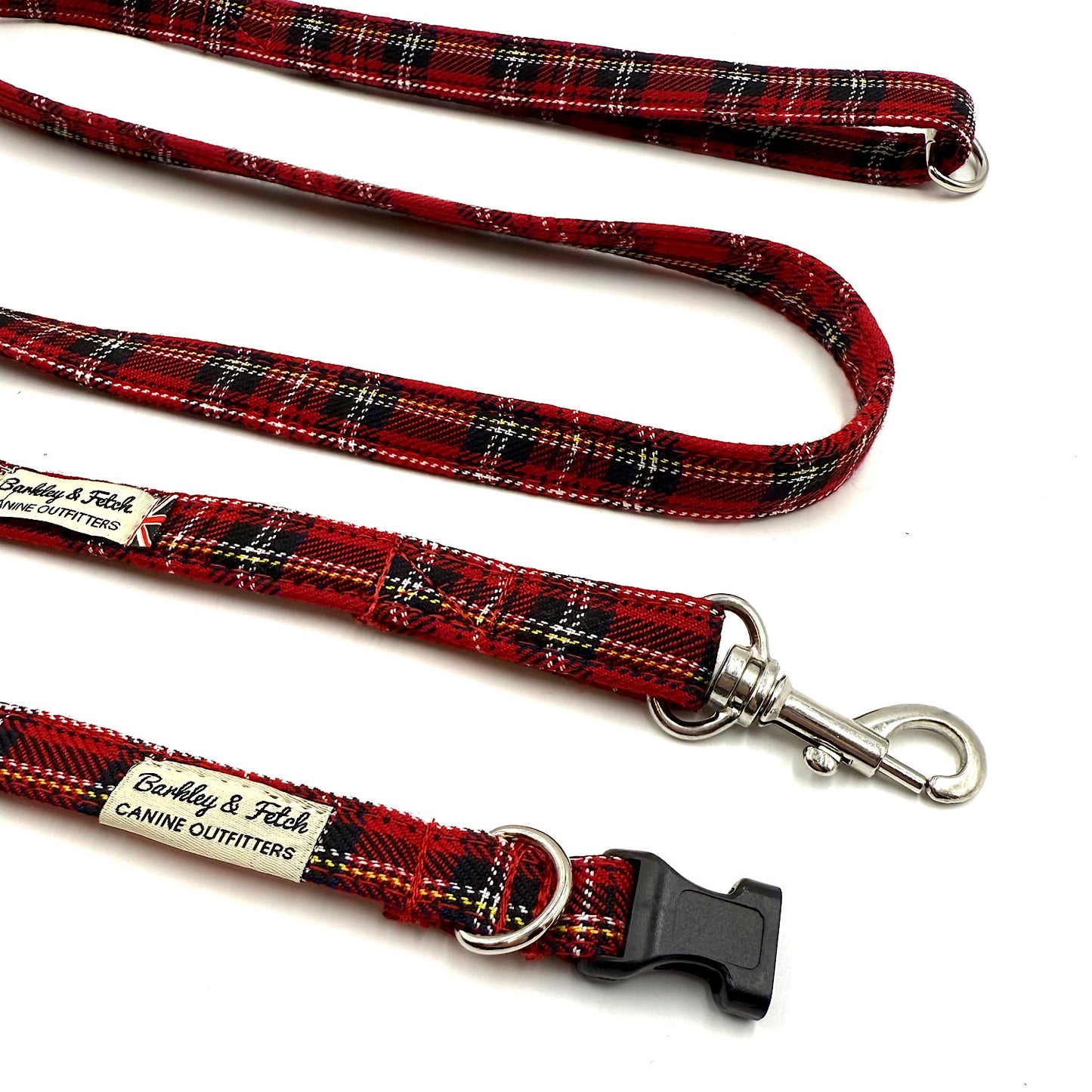 Red plaid dog leash with metal clip and black buckle on a white background
