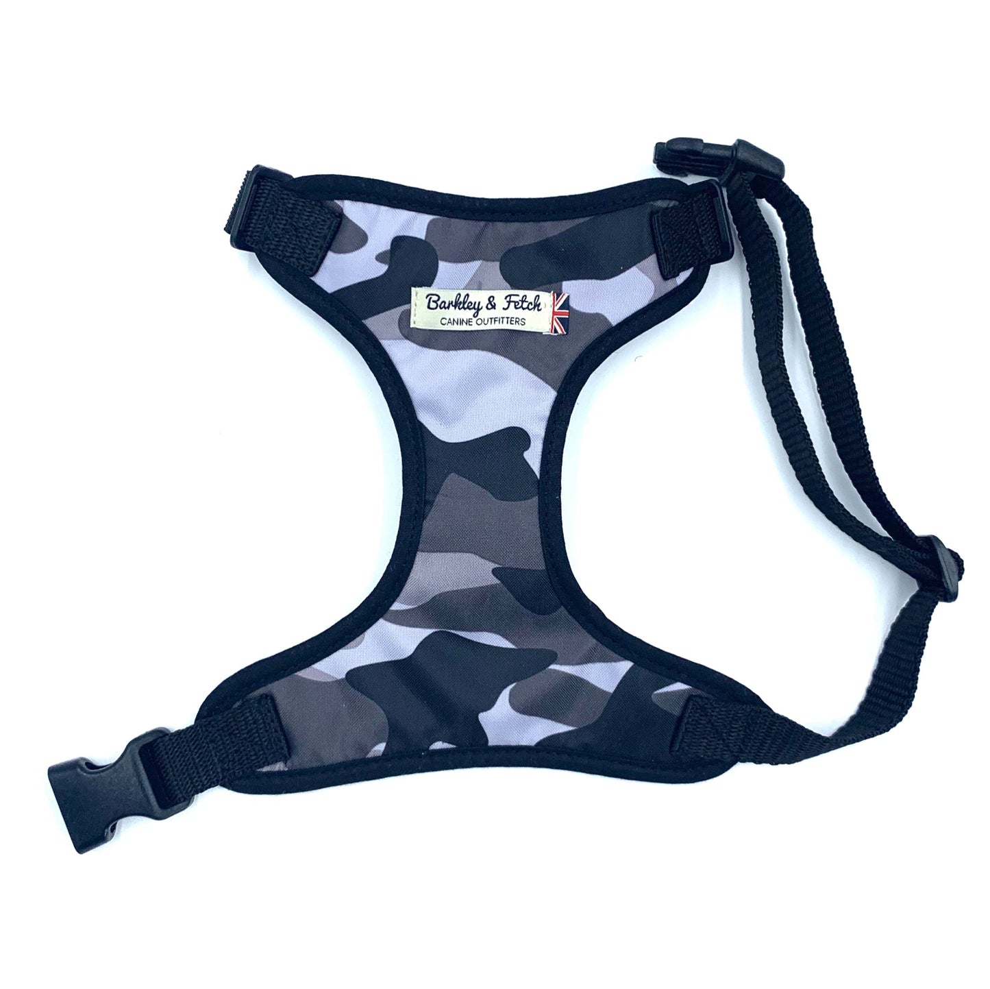 A dog harness with a camouflage pattern, featuring adjustable straps, a heavy-duty d-ring, and a side release buckle.