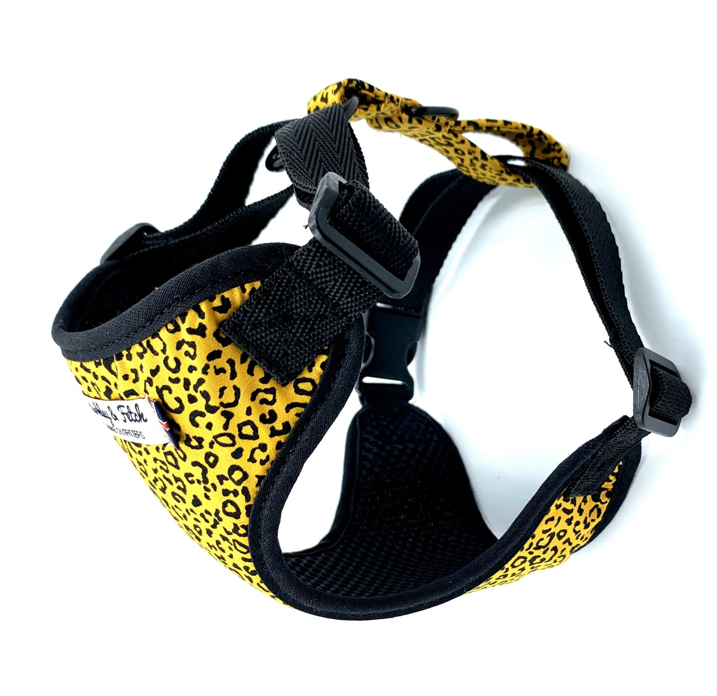 Dog harness with yellow leopard print and black straps on a white background