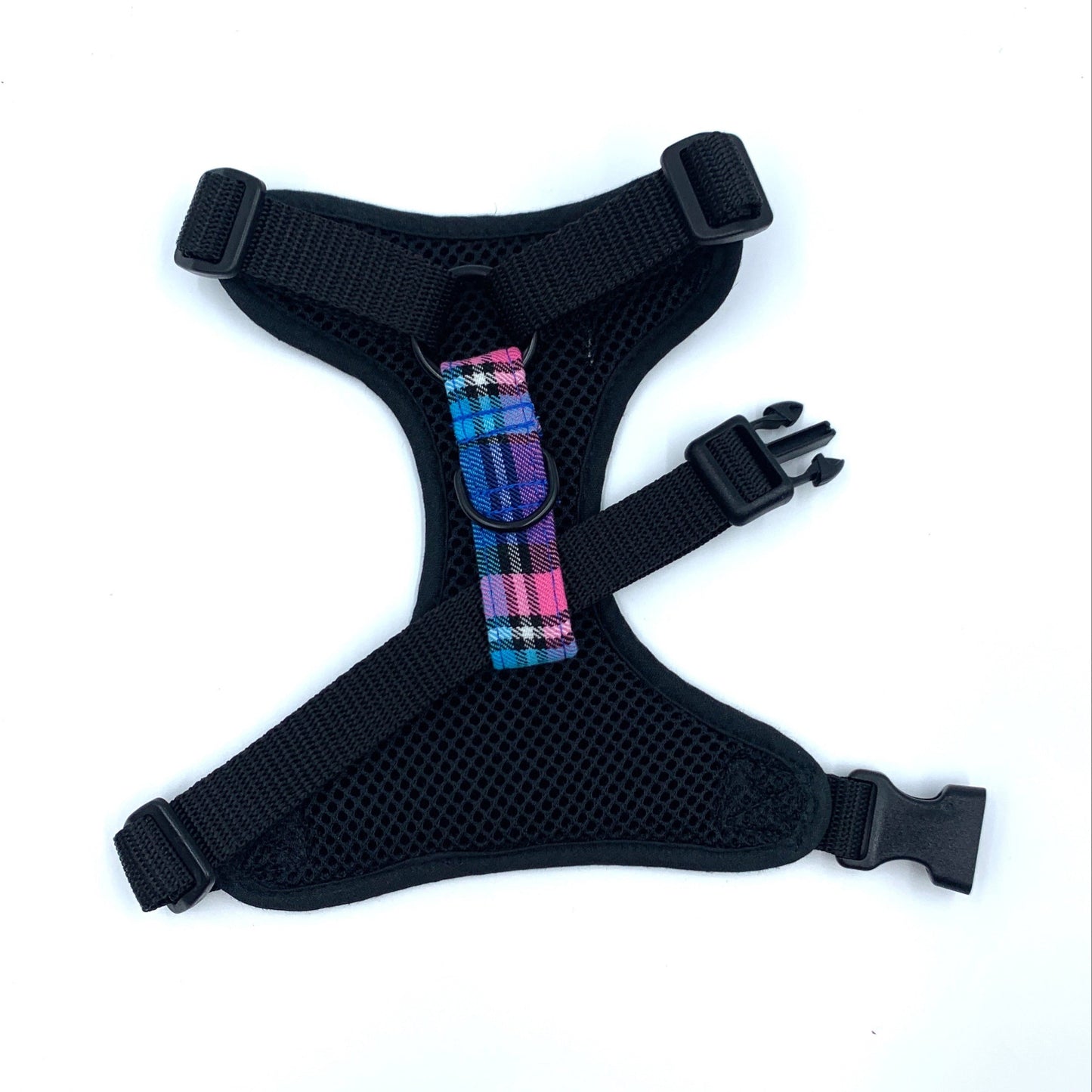 Black dog harness with colorful plaid strap on a white background