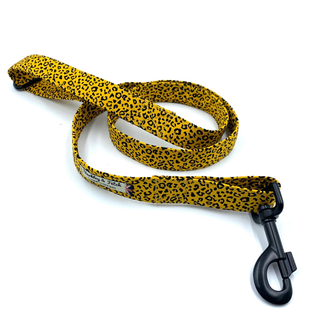 An ochre leopard print dog lead with a metal trigger hook and D-ring on the handle.
