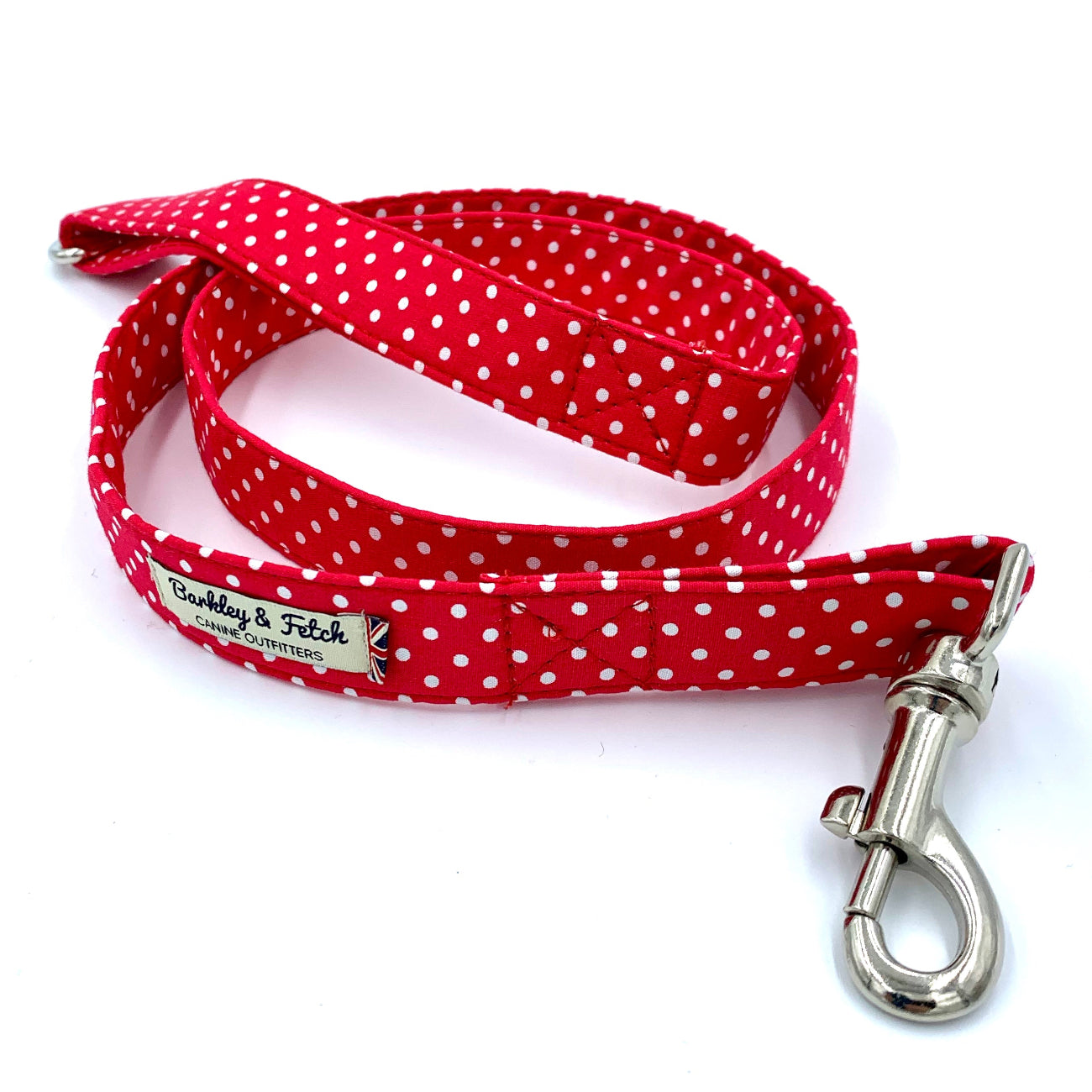 A red and white polka dot dog lead with a metal trigger hook and a D-ring on the handle.