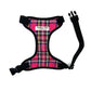 A bright pink tartan fabric dog harness with adjustable straps and a side release buckle.