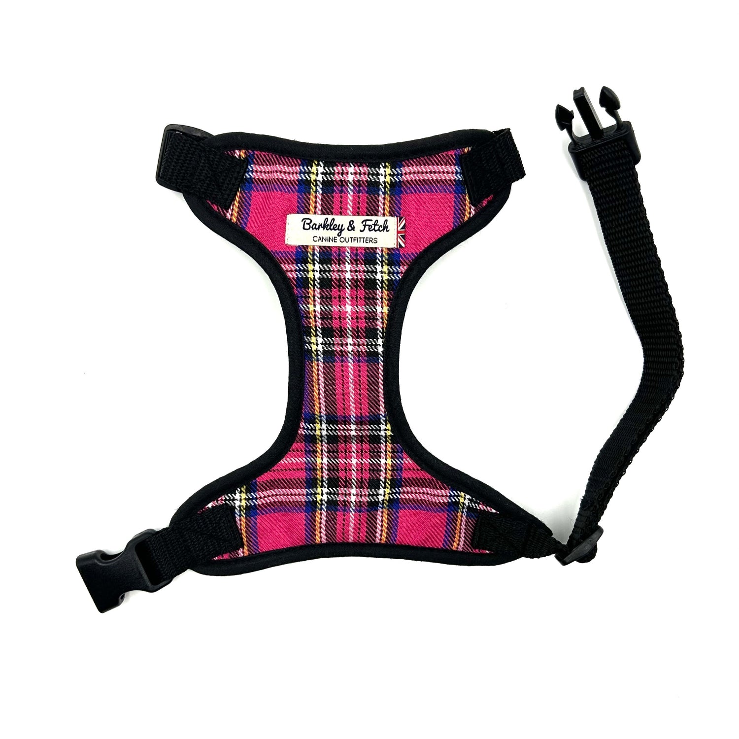 A bright pink tartan fabric dog harness with adjustable straps and a side release buckle.