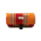 Striped red and orange blanket with a brand label on a white background, handmade in UK by Barkley and fetch