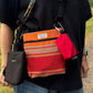 A person wearing a black T-shirt carries a small crossbody bag with a multicolor striped pattern, a bright red pouch, and a black phone case. The brand name 'Barkley and fetch' is visible on the labels.