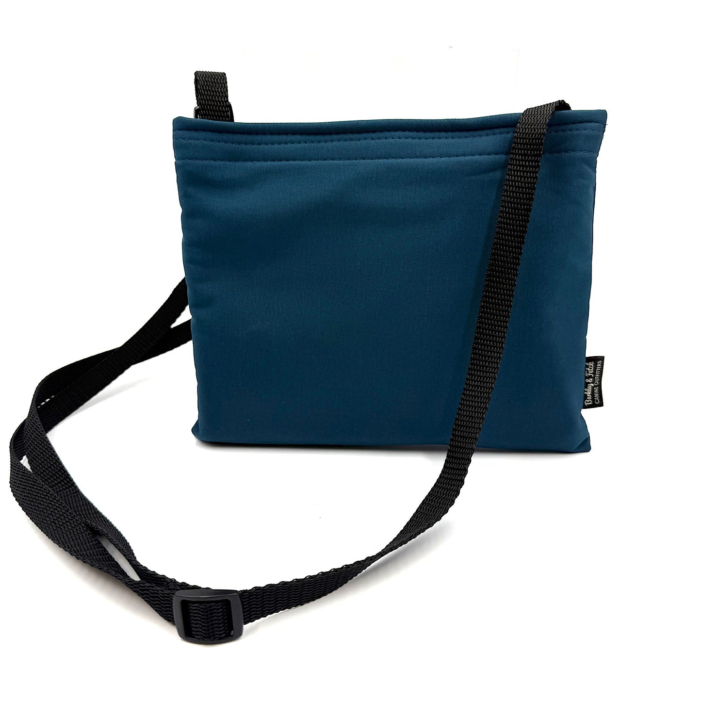 Teal colour settle mat folded into a velcro closed bag with a black shoulder strap handmade by Barkley and fetch in the UK, against a white background