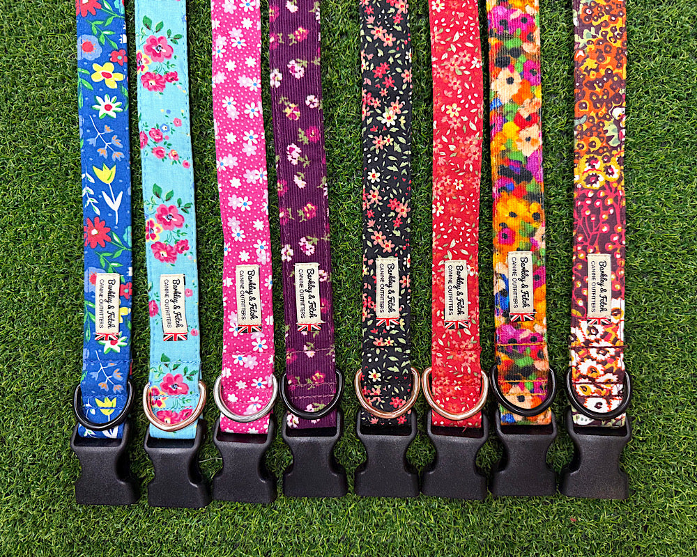 Eight colorful floral dog collars with black plastic quick-release buckles, displayed vertically side-by-side on a green grass background. Handmade by Barkley and fetch
