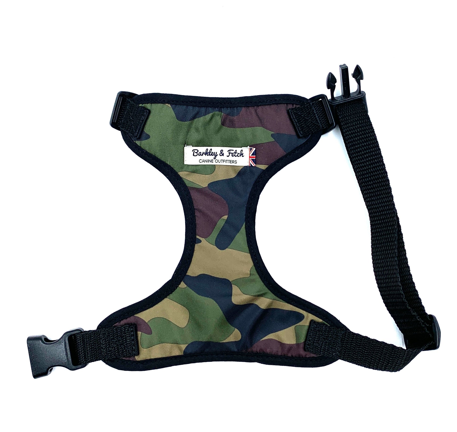 A camo print dog harness with adjustable straps and a metal d-ring, predominantly in green, brown, and black tones.