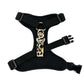 Black dog harness with a leopard print buckle on a white background