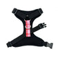 Black dog harness with a pink plaid bow on a white background