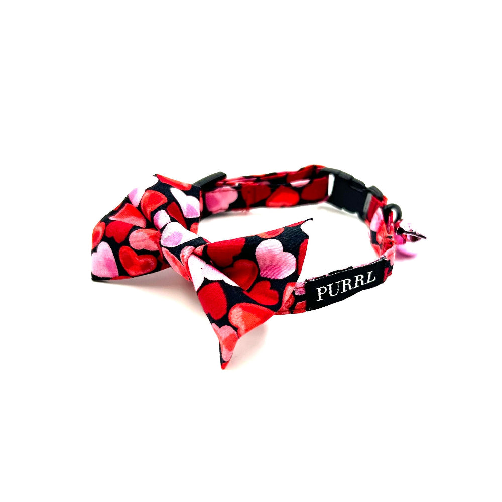 A multicolored PURRL cat collar with a heart pattern, including a breakaway clip, adjuster, d-ring, and bell. The collar is displayed on a white background handmade by Barkley And Fetch