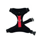Black dog harness with a red and white polka dot buckle on a white background