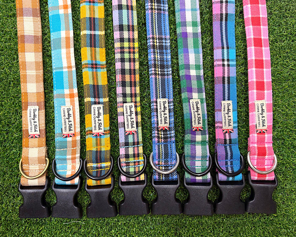 Eight colorful plaid dog collars with black plastic quick-release buckles and metal rings, laid flat on green artificial grass. Each collar has a fabric tag reading Barkley and Fetch