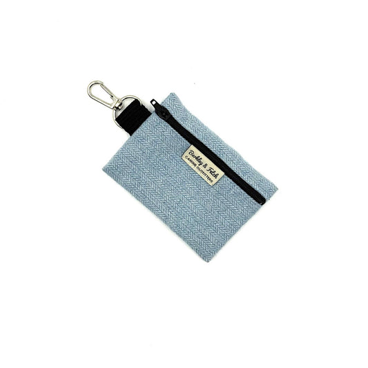 Light blue fabric pouch with black strap and metal clip on a white background