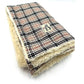 A caramel tartan dog blanket with a plush cream edge, displaying the brand label 'Barkley & Fetch'. handmade by Barkley and Fetch of Great Britain
