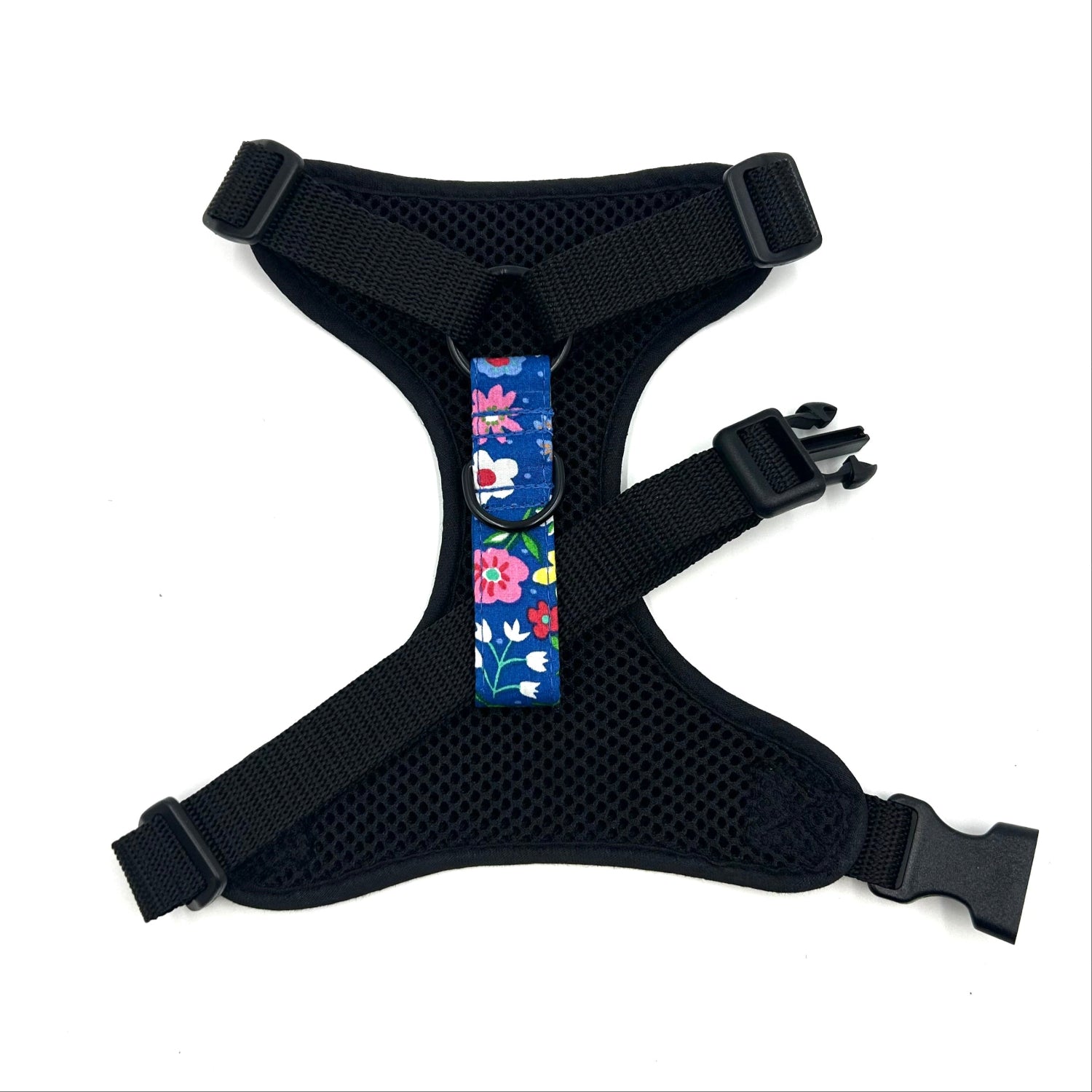 Black dog harness with a colorful floral patch on a white background