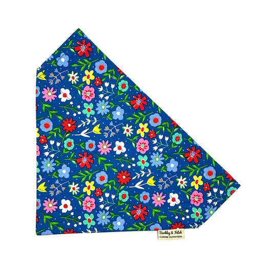 Colorful floral patterned fabric on a blue background with a brand logo at the bottom.