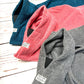 Three bathrobes in blue, pink, and gray on a wooden surface. Handmade by Barkley and Fetch on our UK workshop