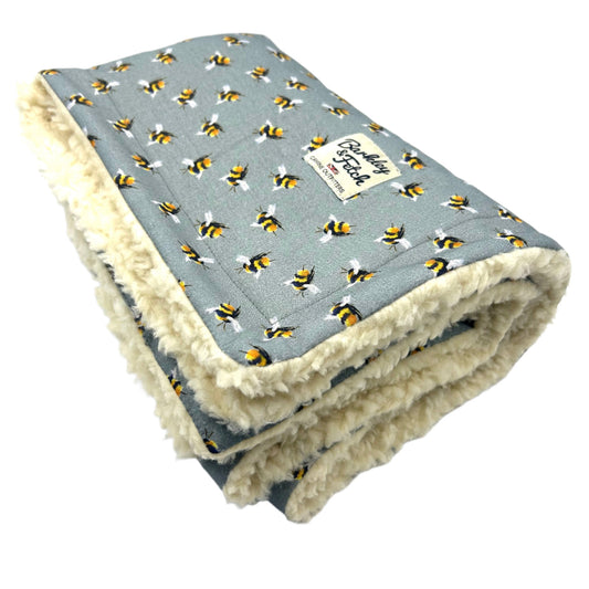 A grey dog blanket with a bee print design, featuring a plush fleece-like texture on the inside handmade by barkley and fetch uk