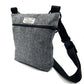 A gray herringbone patterned dog walk and treat bag with an adjustable black shoulder strap and a zip fastening.