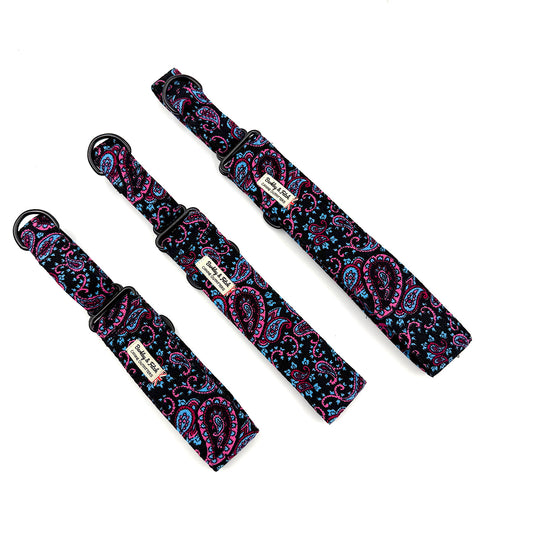 Three black dog collars with pink and blue paisley patterns on a white background