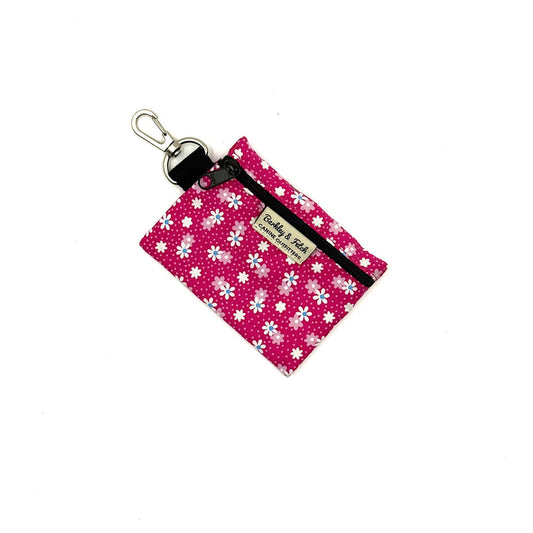 Pink keychain pouch with white floral pattern on a white background
