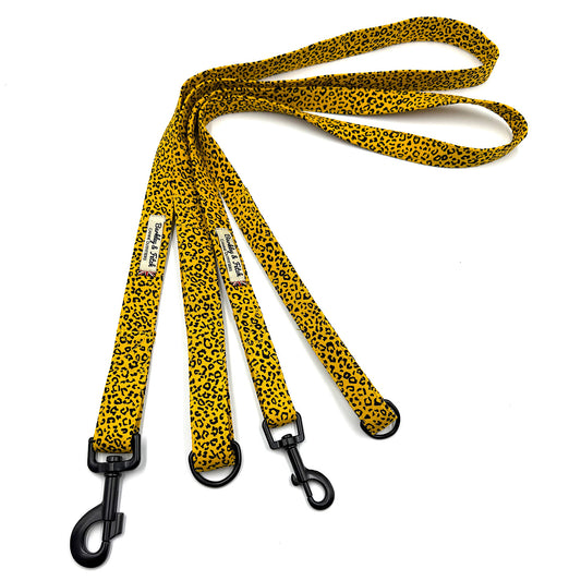 Two yellow leopard print dog leashes with black clips on a white background