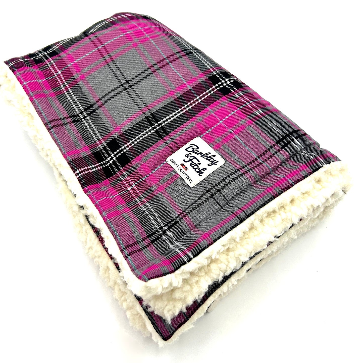 A pink and grey tartan pattern dog blanket with a soft white fleece backing, displaying a branded label on the bottom corner handmade by Barkley and Fetch of Great Britain