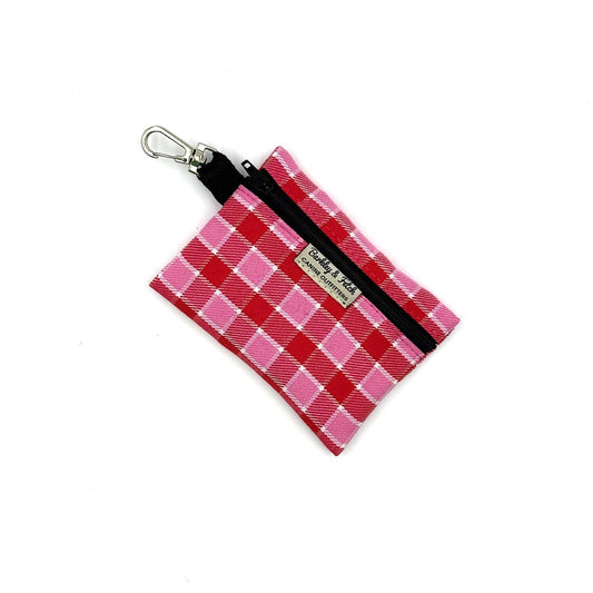 Pink and red plaid pouch with a black strap on a white background