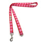 Red and pink plaid dog leash with metal clip on a white background