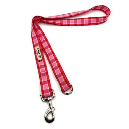 Red and white checkered dog leash with metal clip on a white background
