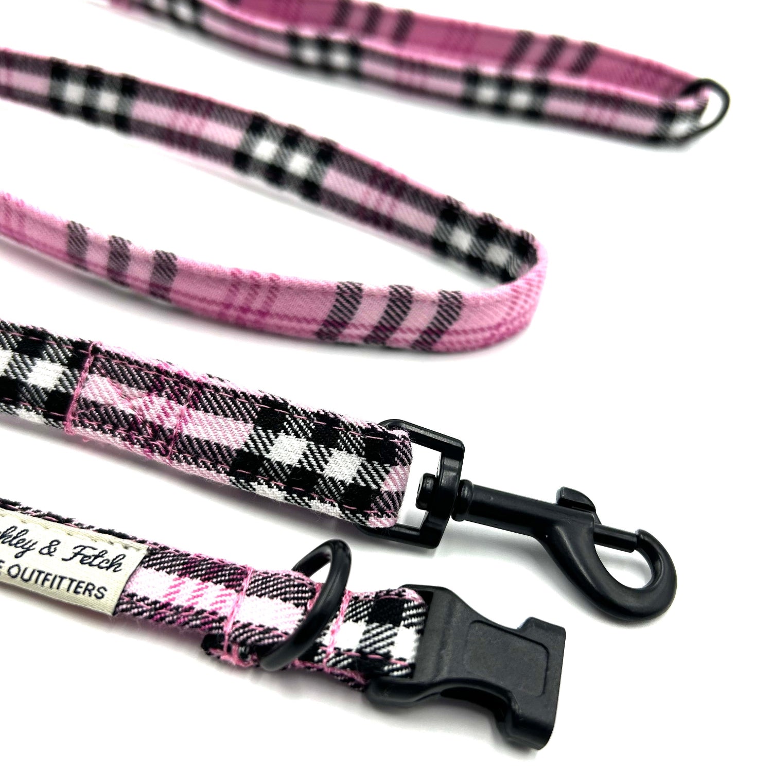 Pink and black plaid dog leashes with a brand label on a white background
