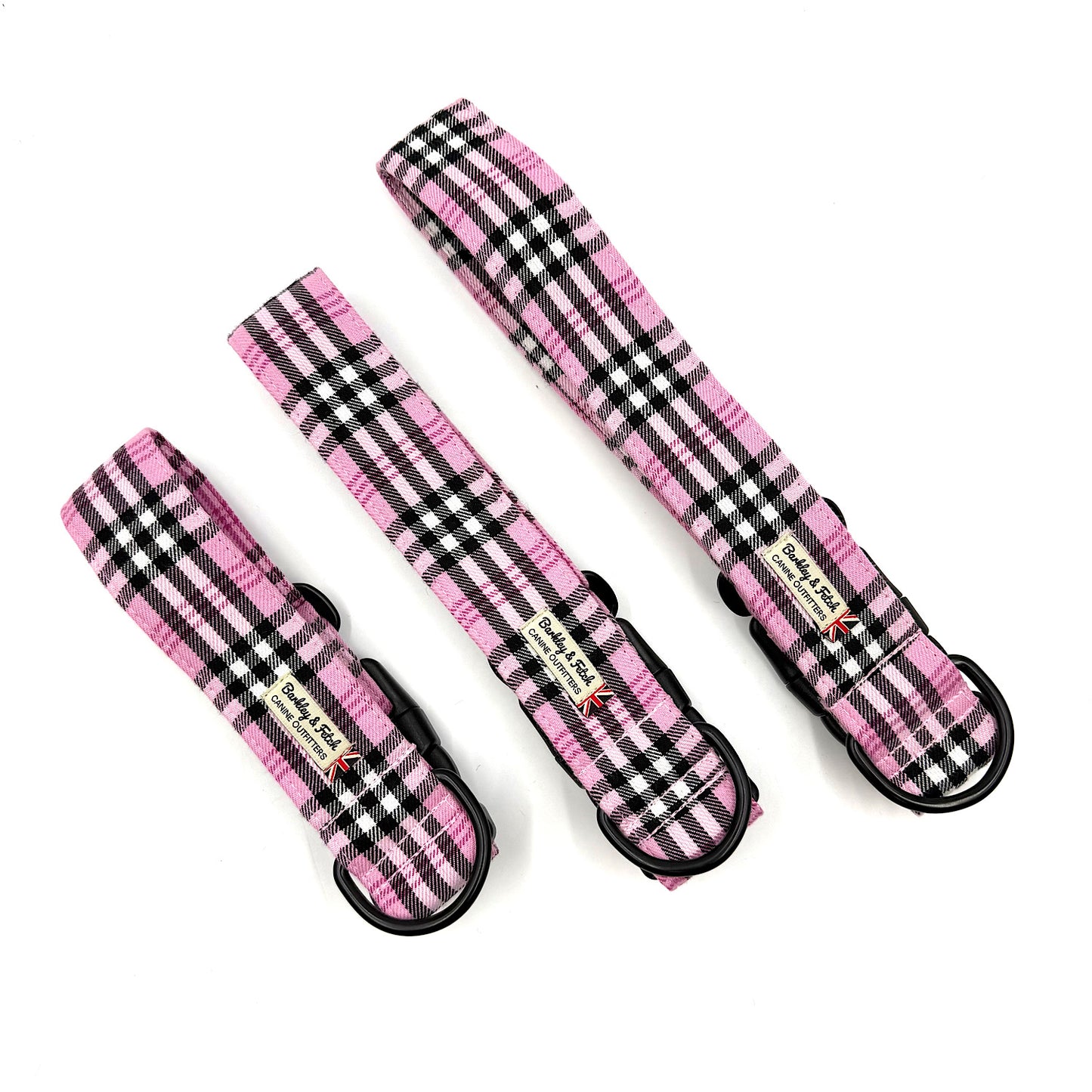 Three pink and black plaid dog collars on a white background