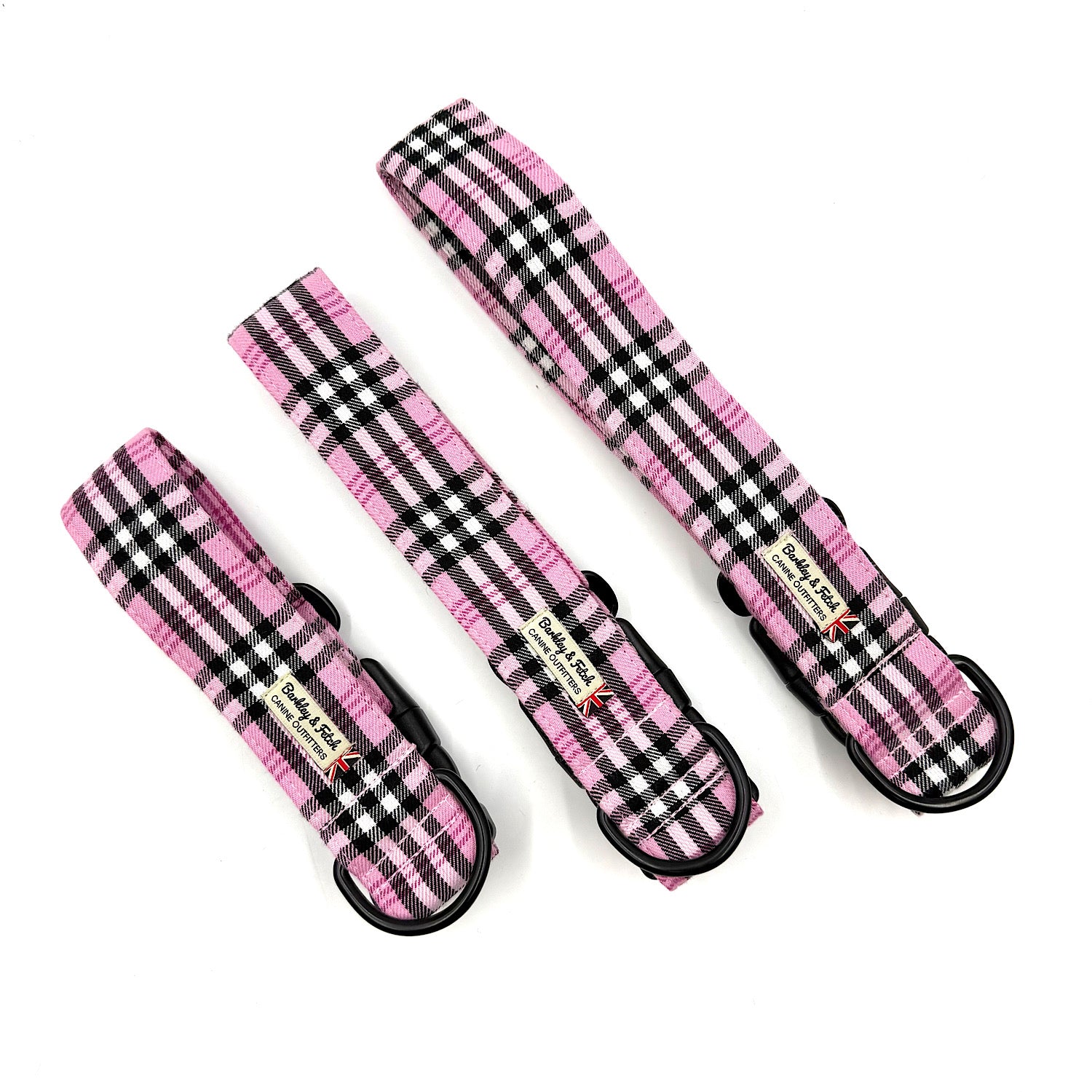 Three pink and black plaid dog collars on a white background