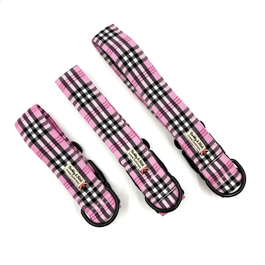 Three pink and black plaid dog collars on a white background