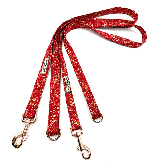 Red flowery dog leash with gold hardware on a white background